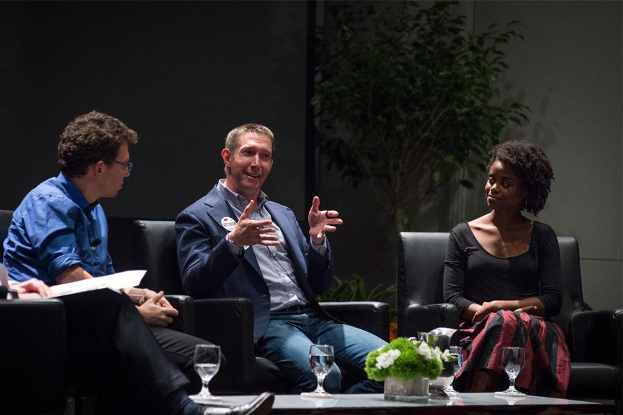 Three people sitting in armchairs, with the two people on the sides listening attentively to the person in the middle who is talking